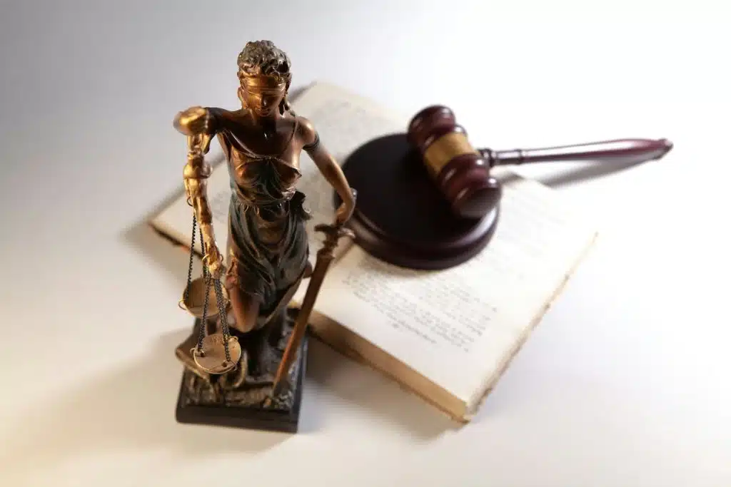 Statue of justice, gavel, and open book on table.