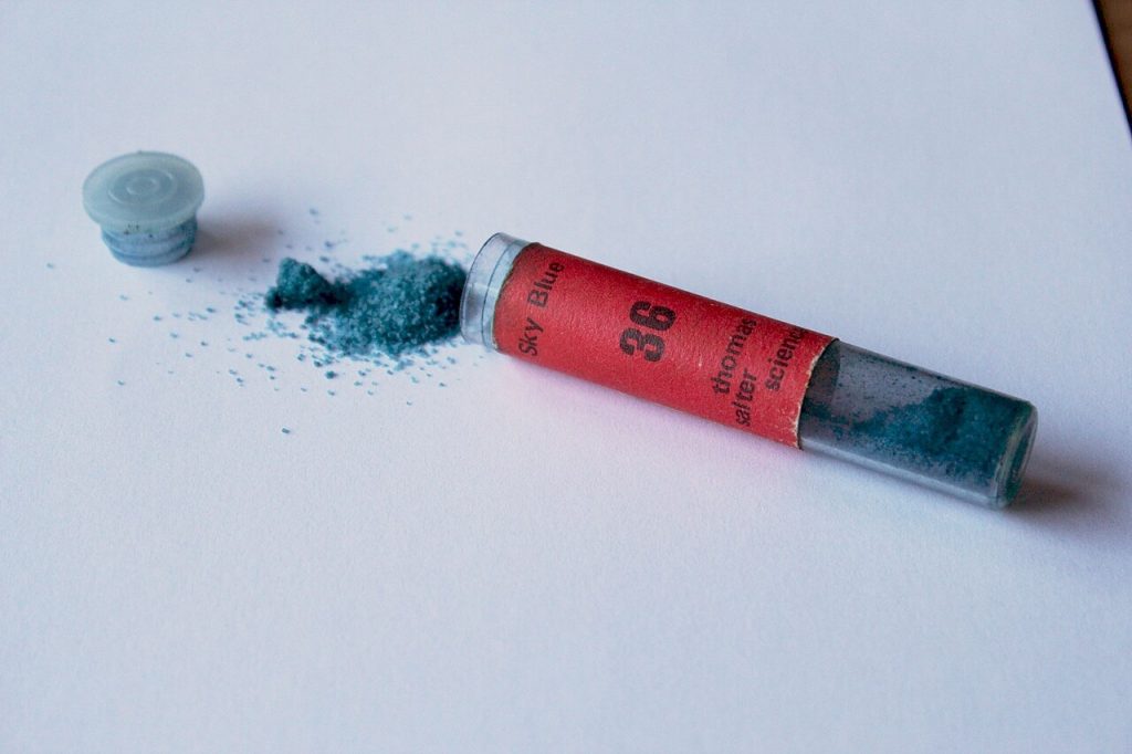 Polvere blu fuoriuscita da una fiala, esempio di colorante in polvere