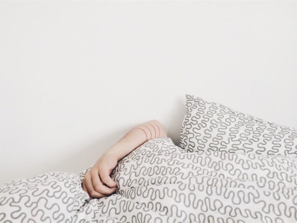 Braccio che spunta da un piumone bianco, a ricordare il sonno e il cloralio idrato